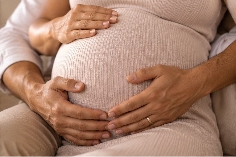casal com as mãos sobre a barriga em ensaio gestante